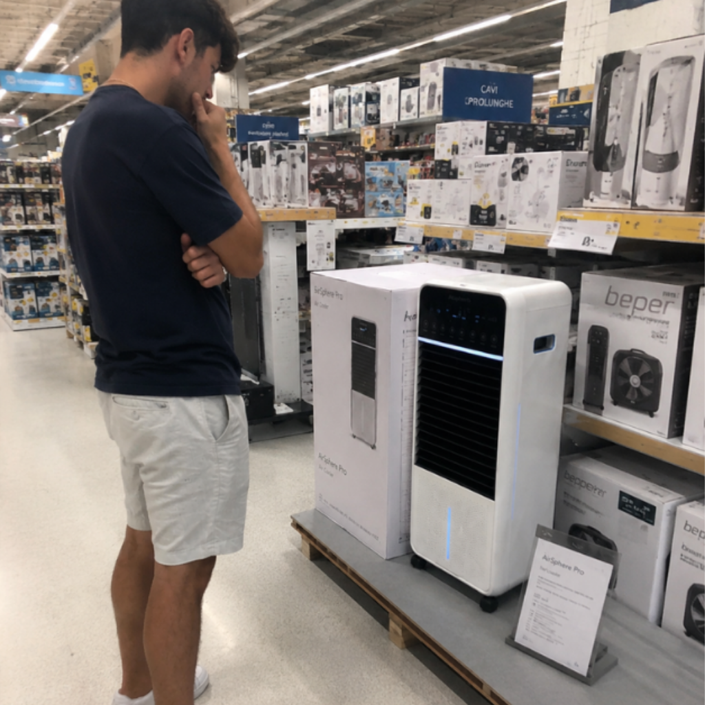Hombre en una tienda mirando un climatizador de columna expuesto